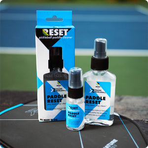 RESET pickleball paddle cleaner packaging and bottles on a pickleball paddle